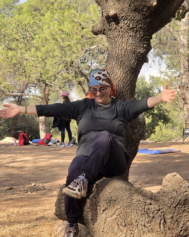 Amal smiling under the trees with a jar of honey