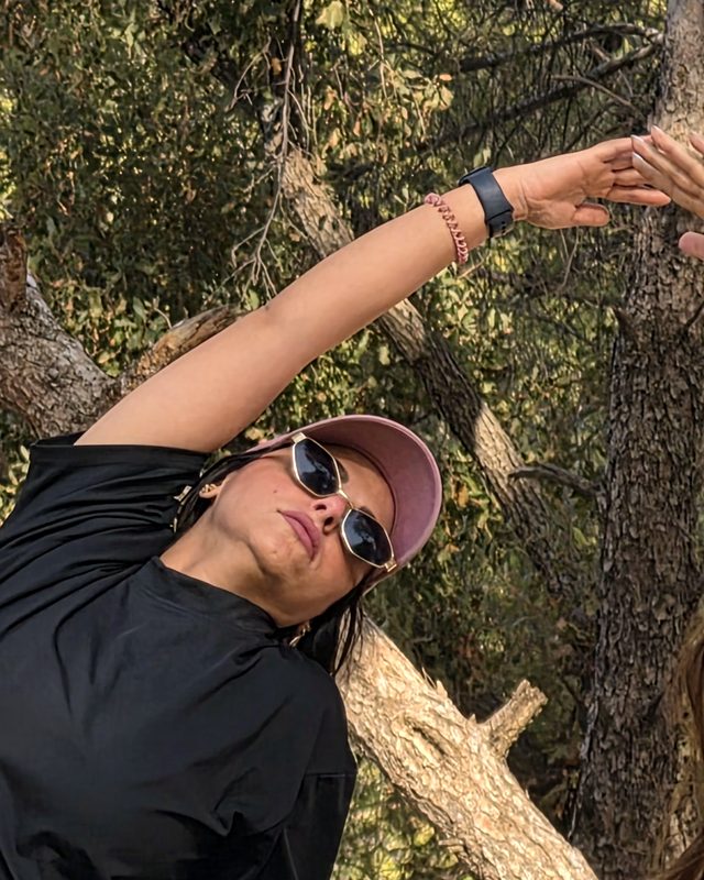 Lara on a rock in her pink cap, facing the forest